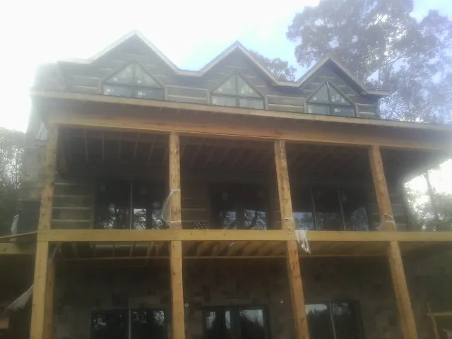 Dormers and porch framing on a large log home under construction — Roof Coating work by our crew in Cortlandt Manor