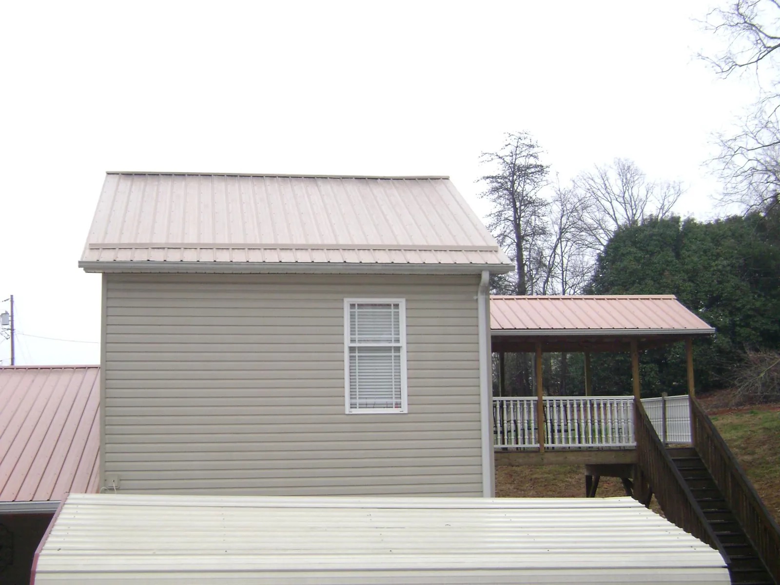 Tan metal roofs on a two story addition and attached porch, from a Roof Replacement job in Cortlandt Manor