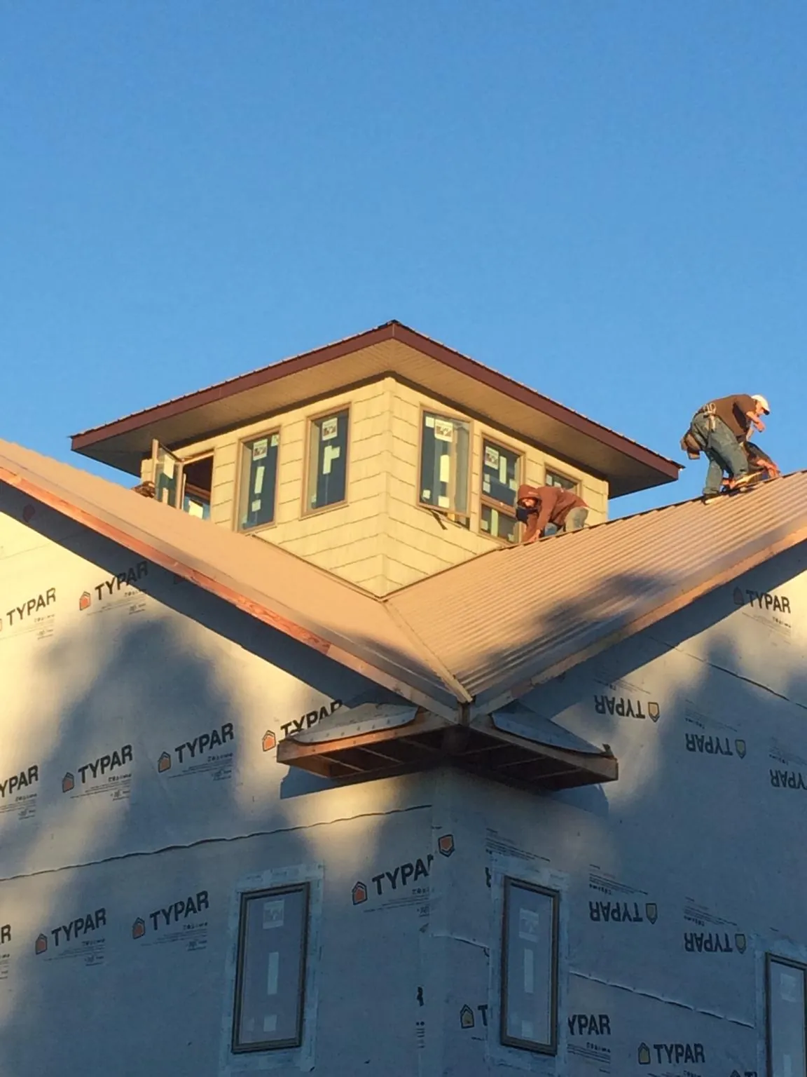 Roofers working around a rooftop cupola on a new metal roof at sunset — Roof Waterproofing in Cortlandt Manor by Roofing Brothers